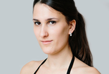 Lächelnde Elena Träger im Profil vor hellem Hintergrund